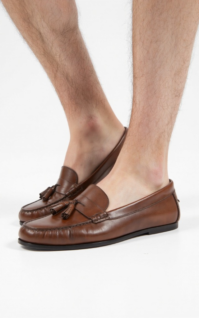 A male model wearing Loafer with tassels, against a white background, with a close   up of the feet